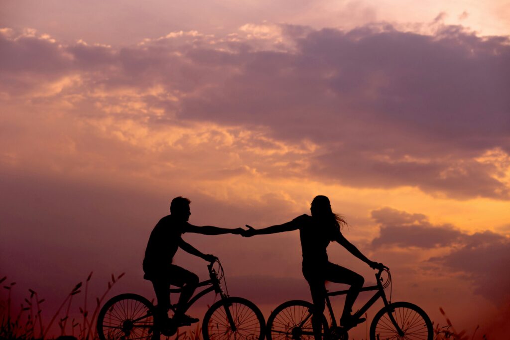 couple biking and holding hands in the sunset