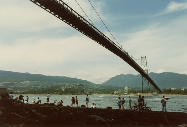 5 day trip vancouver itinerary. A group of people standing under a suspension bridge. In the anticipation of an aircraft carrier making its way under the Lions Gate Bridge in August of 1992, crowds slowly formed.

vancouver
stanley park drive
bc
canada
bridge
water
british columbia
west vancouver
north vancouver
trees
park
stanley park
1992
retro
ocean
mountains
view
building
human
person
